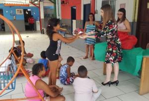 A juíza Juliana  Kalichsztein entrega os presentes para uma das crianças atendidas por abrigos vinculados à Vara da Infância de Caxias