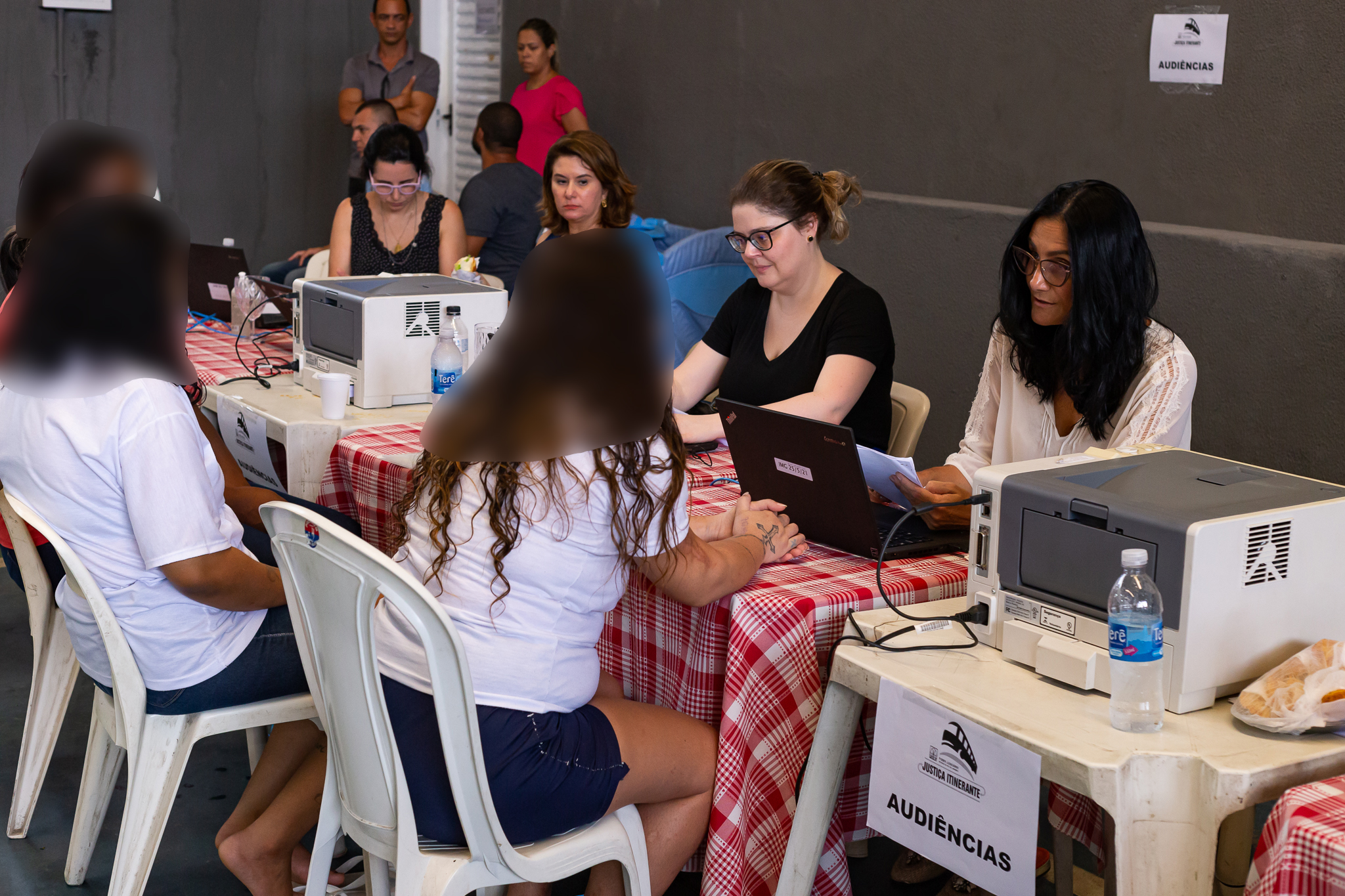 Do lado esquerdo apenadas sentadas, do lado direito, juízas oferecem atendimento.