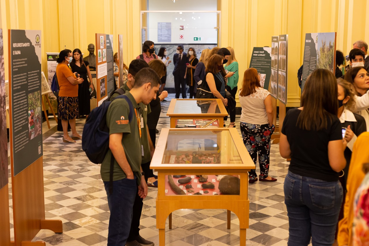 A imagem mostra visitantes da exposição "Refloresta Rio", no salão dos Espelhos do Museu da Justiça.
