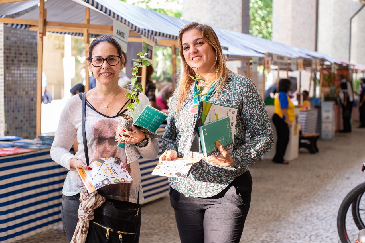 A imagem mostra Rosane Bahia e Luciana Possebon segurando mudas e planfletos que receberam durante visita à Feira de Sustentabilidade do TJ