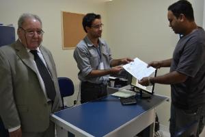 O tabelião do 13° Cartório de RCPN, Sr. Elizio Chagas, e o escrevente, Jean, entregam a certidão de nascimento de Beatriz ao pai.