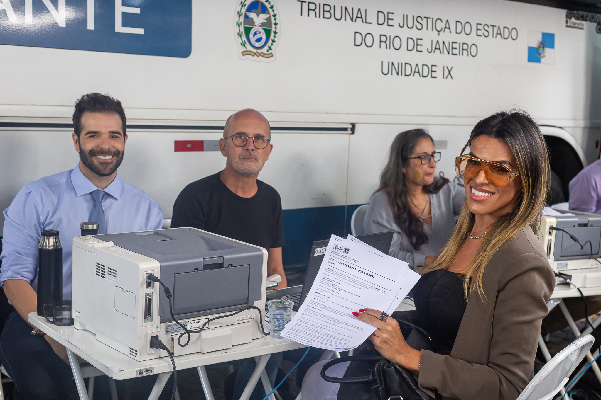 Juiz Eric Scapim sentado de azul e do outro lado da mesa Gabriela Oliveira 