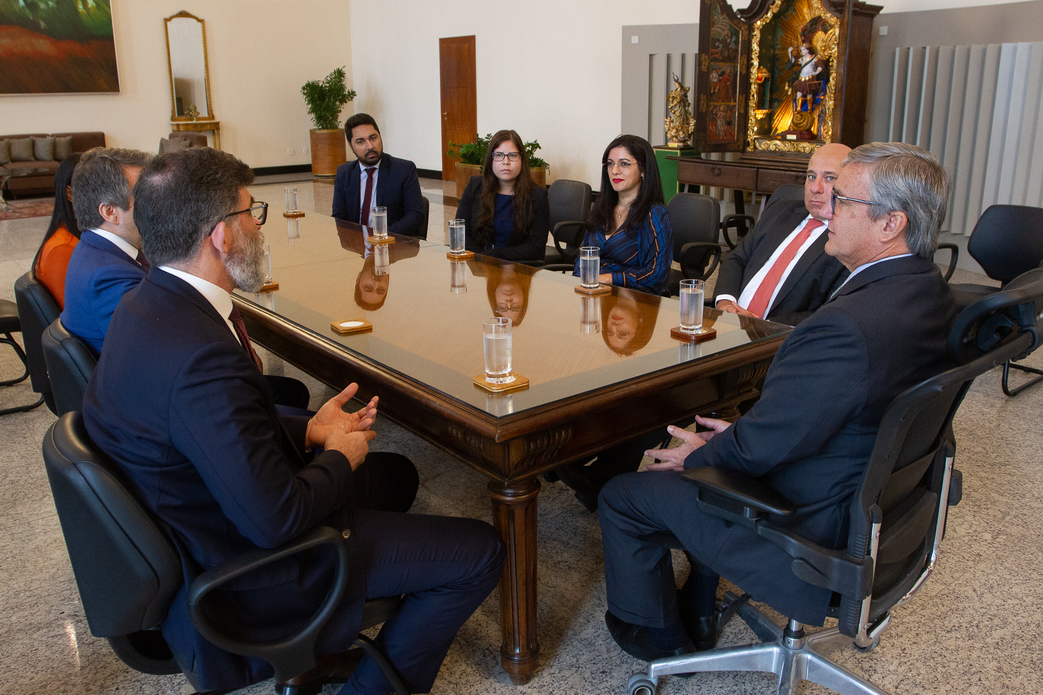 Fotografia colorida no Salão Nobre do Tribunal de Justiça durante reunião entre representantes do TJRJ e OAB. Participantes da reunião sentados em volta de uma mesa retangular. 