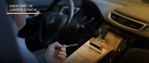 #ParaTodosVerem: Acima, no canto esquerdo, o texto “EMENTÁRIO DE JURISPRUDÊNCIA”. Imagem azul-amarelada do lado interno dianteiro de um automóvel, com o volante à esquerda, e, à direita, um homem portando uma caneta, com uma prancheta e um formulário ao colo.