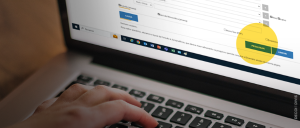 #ParaTodosVerem: Metade da imagem consiste na tela de pesquisa jurisprudencial em branco e amarelo; a outra, no teclado do laptop cinza e preto e, sobre ele, mão branca digitando.