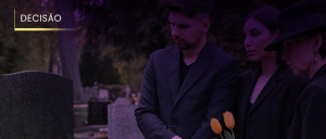 Imagem de um homem e duas mulheres, uma delas segura flores, ao lado de um jazigo em um cemitério