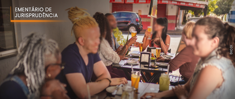 #ParaTodosVerem: Acima, no canto esquerdo, o título “EMENTÁRIO DE JURISPRUDÊNCIA”. Imagem de várias pessoas, pretas e brancas, interagindo sentadas, às mesas externas de um bar.