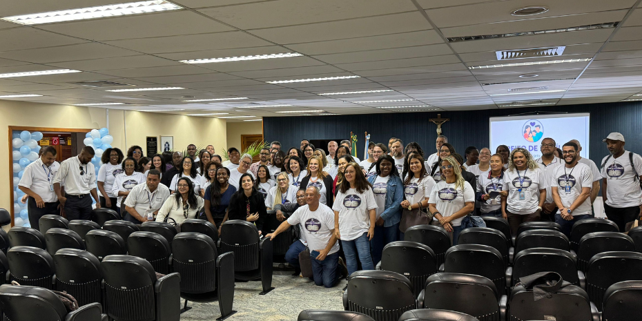 A imagem mostra o grupo de alunos dentro de um auditório.