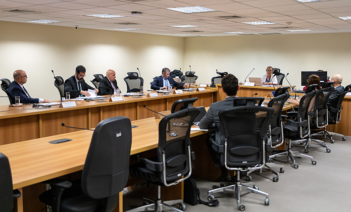A imagem mostra cerca de 10 pessoas sentadas em torno de uma mesa de reunião com destaque para a 2ª vice-presidente do TJRJ, desembargadora Maria Angélica Guimarães