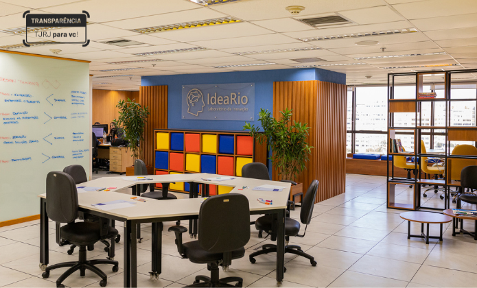 imagem mostra espaço com parede colorida, mesa e  assentos