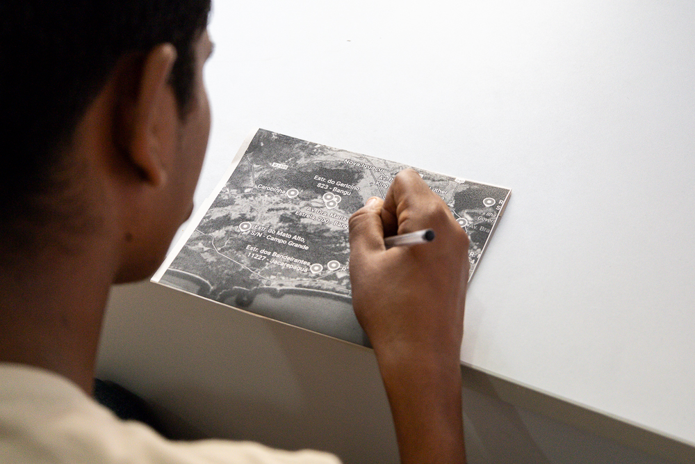 Jovem risca rotas sobre mapas na foto com imagem em preto e branco