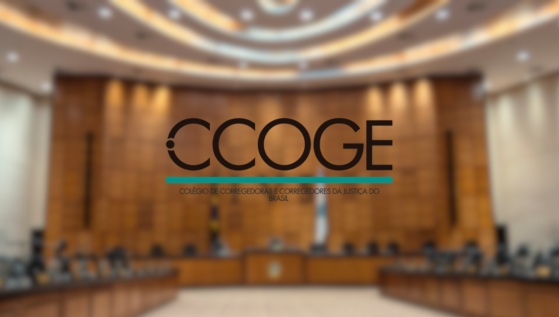 A imagem mostra o Plenário Ministro Waldemar Zveiter, no Tribunal da Justiça do Rio de Janeiro (TJRJ). O ambiente é amplo, com revestimento em madeira nas paredes e uma arquitetura imponente, marcada por um teto curvo com iluminação embutida, que transmite formalidade e solenidade. No centro da imagem, em destaque, aparece o logotipo “CCOGE”, acompanhado do texto: “Colégio de Corregedoras e Corregedores da Justiça do Brasil”, sublinhado por uma linha horizontal em tom verde-azulado. Ao fundo, é possível perceber uma mesa em formato semicircular, típica de sessões colegiadas, com cadeiras distribuídas ao longo dela. Também se notam bandeiras oficiais posicionadas atrás da mesa central, reforçando o caráter institucional e jurídico do espaço. A imagem está propositalmente desfocada no fundo, o que direciona a atenção para o logotipo e o nome da instituição.