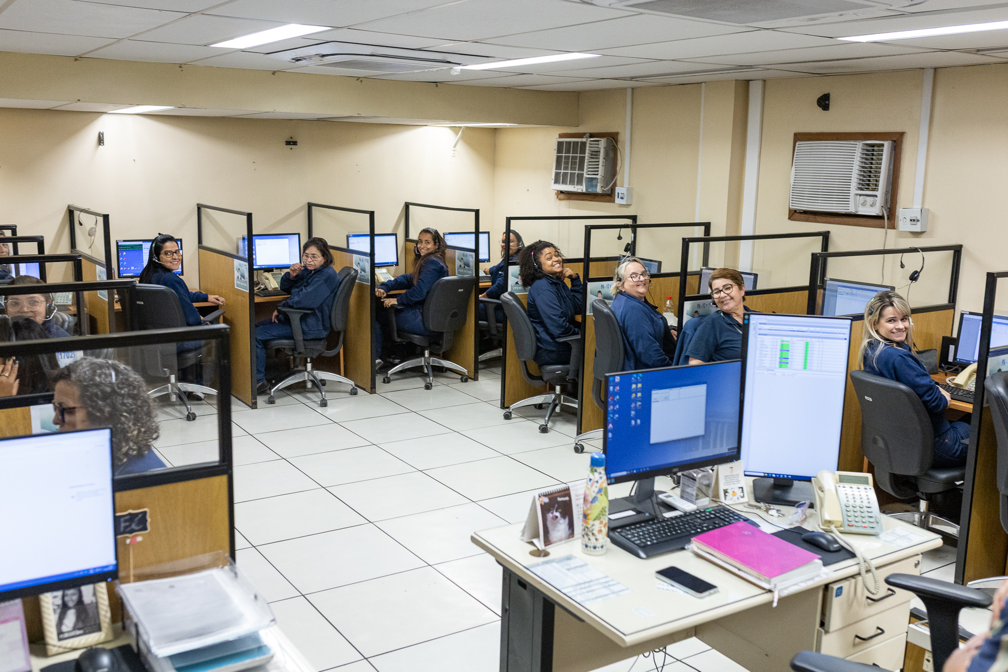 Foto mostra telefonistas sentadas em suas cabines de atendimento