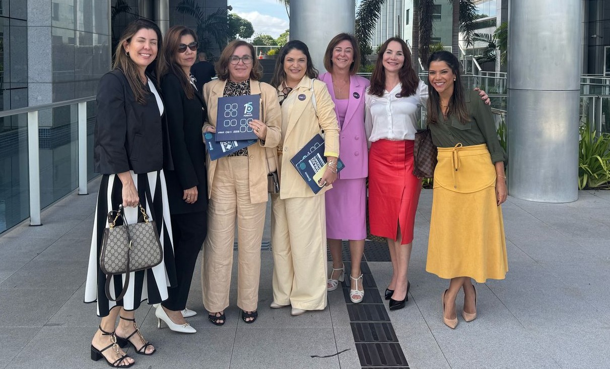Sete mulheres, todas magistradas do Tribunal de Justiça do Rio, trajando roupas de diferentes modelos e cores, todas de cabelos longos ou semi-longos nas cores castanho escuro e castanho claro, posam juntas em ambiente externo, de piso cinza, onde aparecem pilastras largas e redondas, áreas ajardinadas e edifícios ao fundo. O espaço tem a característica de ser um pátio interno de acesso a um dos prédios 