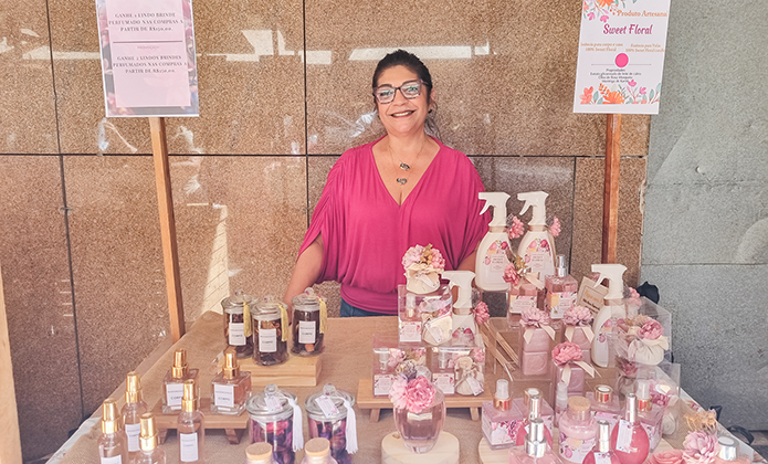 Mulher com blusa rosa exibe as fragrâncias à venda na feira do TJRJ