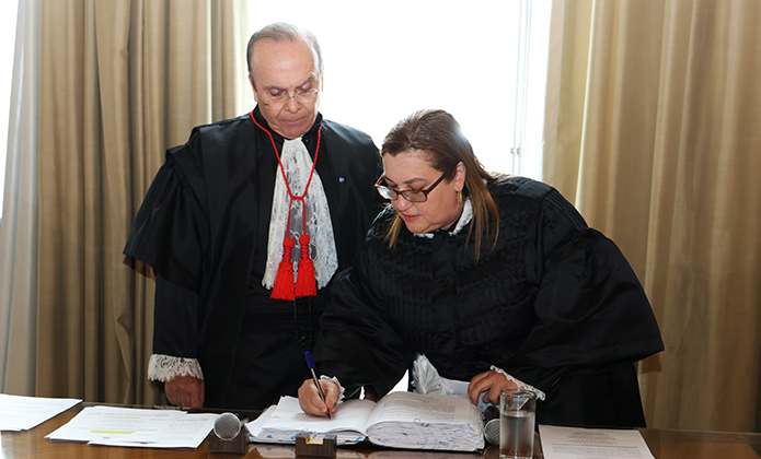 Juíza Claudia Márcia Gonçalves Vidal assina o termo de posse sob o olhar do presidente do TJRJ, desembargador Ricardo Rodrigues Cardozo