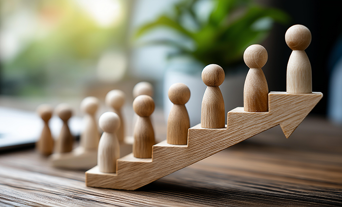 #ParaTodosVerem: Imagem mostra pequenas figuras de madeira alinhadas sobre uma seta inclinada para cima, sugerindo crescimento ou progressão.